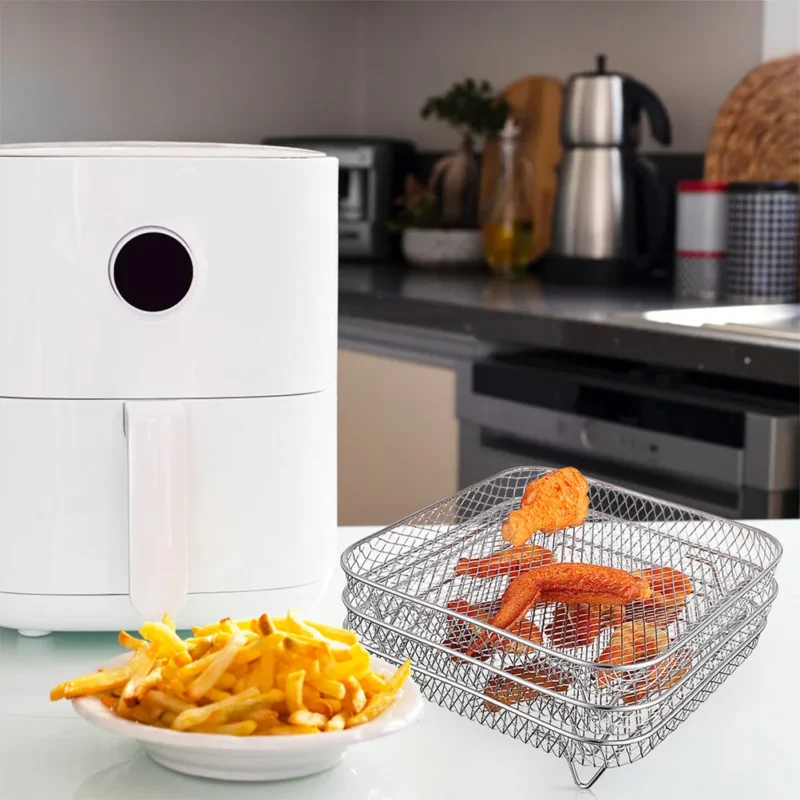 Staplade fyrkantiga nätgaller för airfryer med kycklingvingar på en köksbänk
