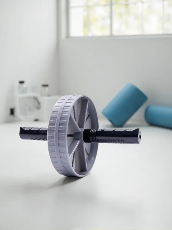 Grått magrullhjul på golvet i ett ljust hemmagym med foamrollers