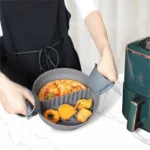 Grått silikoninlägg för airfryer med mat som lyfts ut bredvid en airfryer
